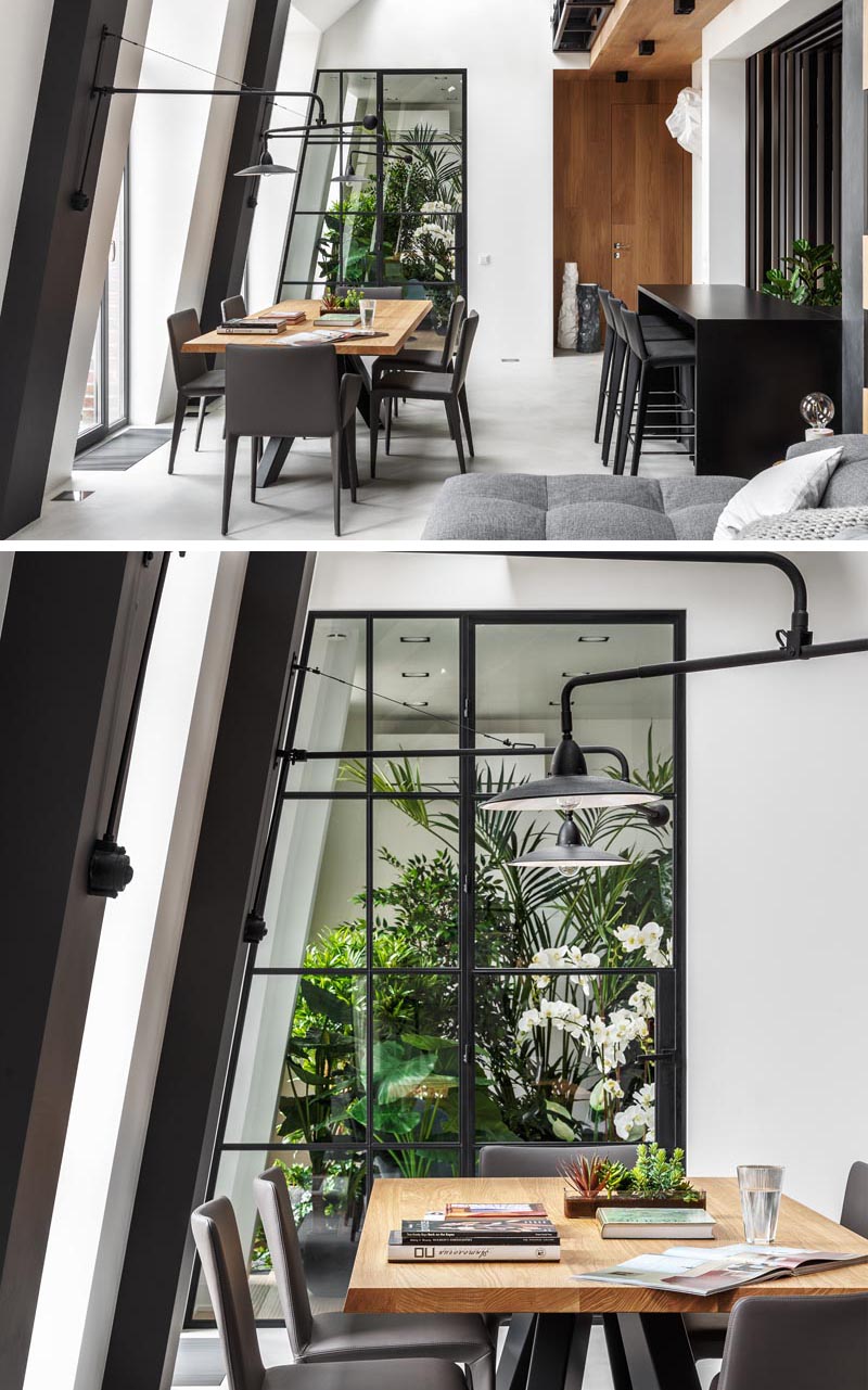 This modern apartment features an indoor plant room that can be seen through a black-framed glass wall, with a door that opens to reveal a quiet and peaceful sitting area. #IndoorGarden #IndoorPlantRoom #IndoorGardenRoom #ReadingNook #InteriorDesign