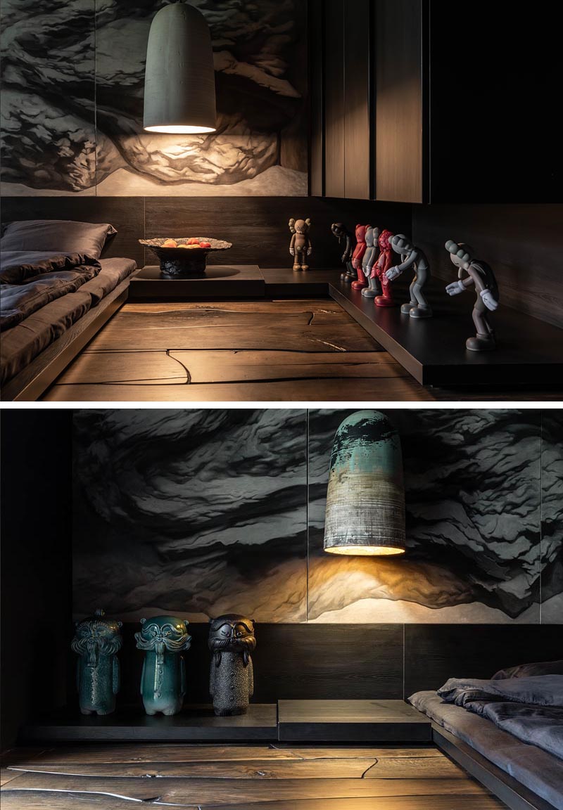 Low dark wood shelves lie below oversized pendant lights, and wrap around this modern bedroom. The shelves provide a place to showcase Kaws sculptures and ceramic art-toys named DIDO, that were also created by Sergey Makhno. #ModernBedroom #MasculineBedroom #DarkBedroom #MoodyBedroom