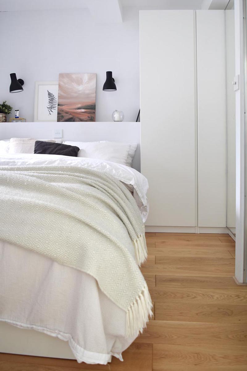 In this modern bedroom, tall closets make use of the space beside the bed, while a built-in shelf allows for the display of art and decor. #BedroomDesign #ModernBedroom