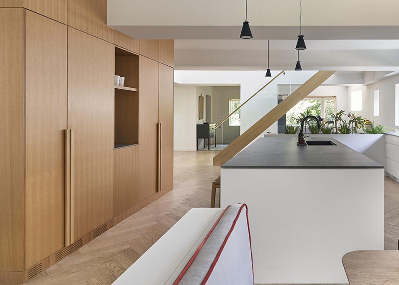 This modern built-in kitchen wood cabinetry lines an entire wall, and features a open coffee station and minimalist hardware, that matches the cabinets and runs all the way to the door. #KitchenHardware #KitchenCabinets #WoodCabinets #WoodKitchen #KitchenIdeas