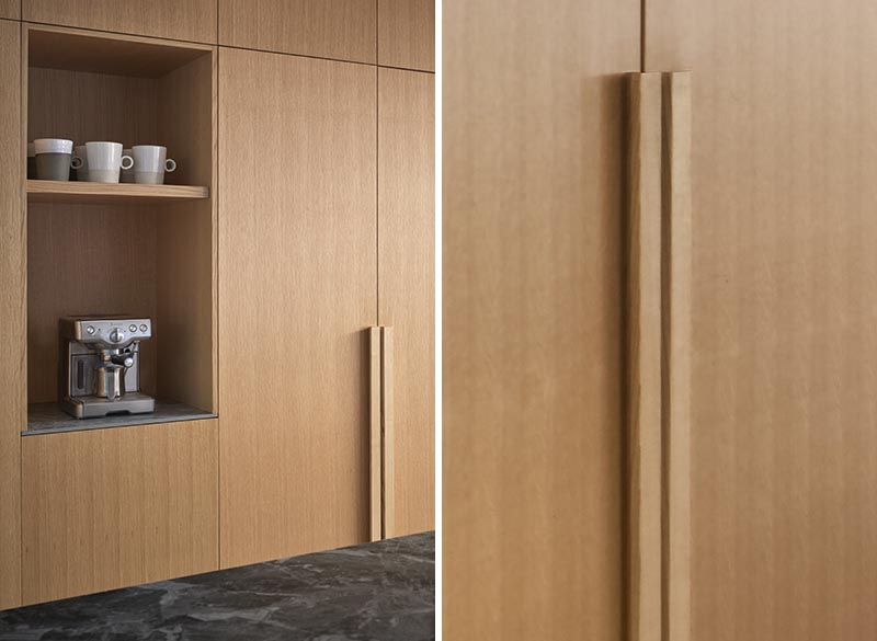 This modern built-in kitchen wood cabinetry lines an entire wall, and features a open coffee station and minimalist hardware, that matches the cabinets and runs all the way to the door. #KitchenHardware #KitchenCabinets #WoodCabinets #WoodKitchen #KitchenIdeas