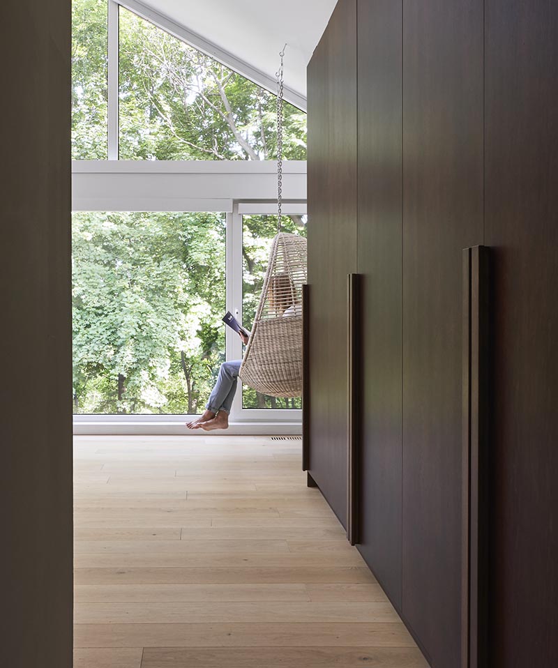 This modern bedroom has built-in dark wood cabinets that have a minimalist handle that runs all the way to the bottom of the cabinet.