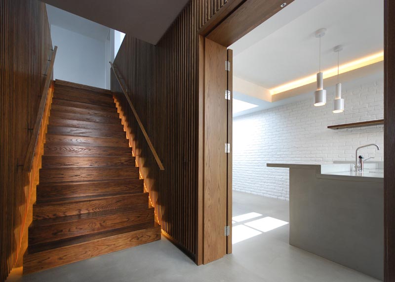 This modern house has a staircase with wood slat walls, handrails on both sides, and hidden lighting. #StairDesign #WoodStairs #StairLighting #HiddenStairLighting #StairHandrails