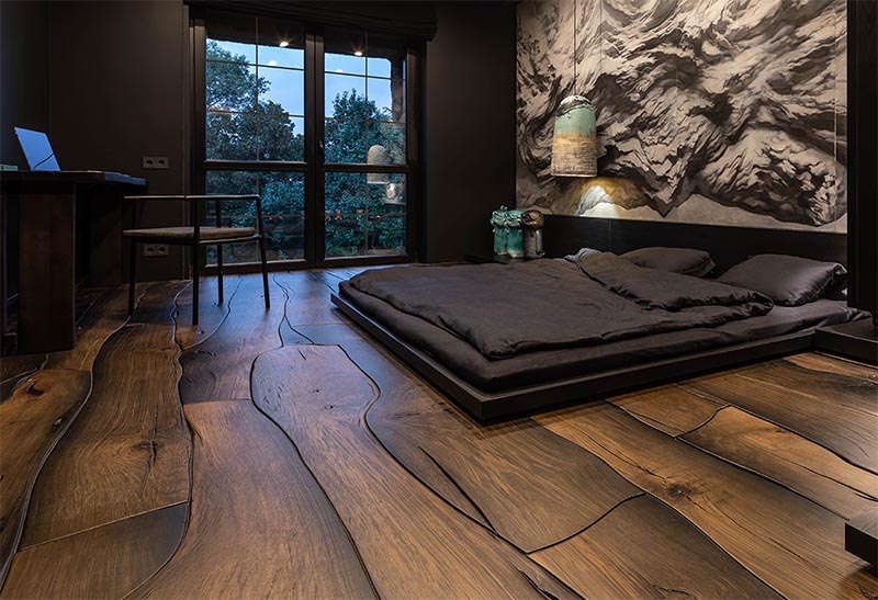 This modern bedroom features a unique wood floor made from 500-year-old oak, that fits together like puzzle pieces and showcases the natural grain, cracks, and knots.