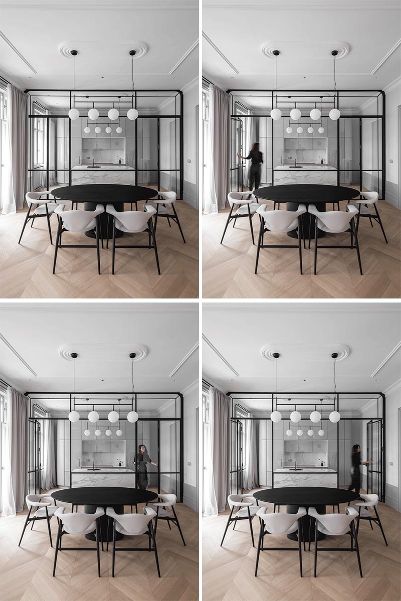 This updated apartment features an eye-catching, black steel framed glass wall that separates the kitchen from the dining room. There's also a grey marble island that complements the grey kitchen cabinets. #ModernKitchen #GlassWall #InteriorDesign #Interiors #GlassPartition