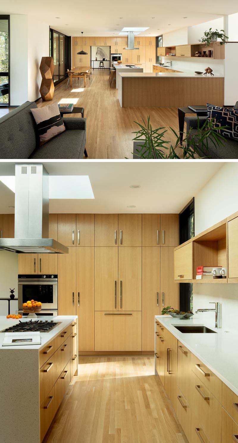 The dining area and kitchen in this modern interior are spacious, with the kitchen designed with custom handcrafted oak cabinets, quartz countertops, and a pair of skylights. #ModernWoodKitchen #QuartzCountertops #ModernKitchen #LightWoodKitchen