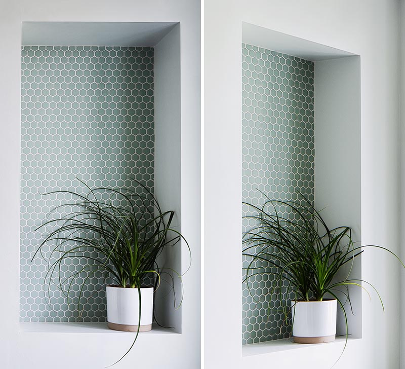 This modern bathroom features a recessed shelf, which is large enough to display a plant, and includes small hexagon penny tiles with white grout. It also helps to add a pop of color to the plain grey wall, and draws attention away from the toilet below. #BathroomShelf #BathroomIdeas #RecessedShelf #PennyTile #BathroomDesign