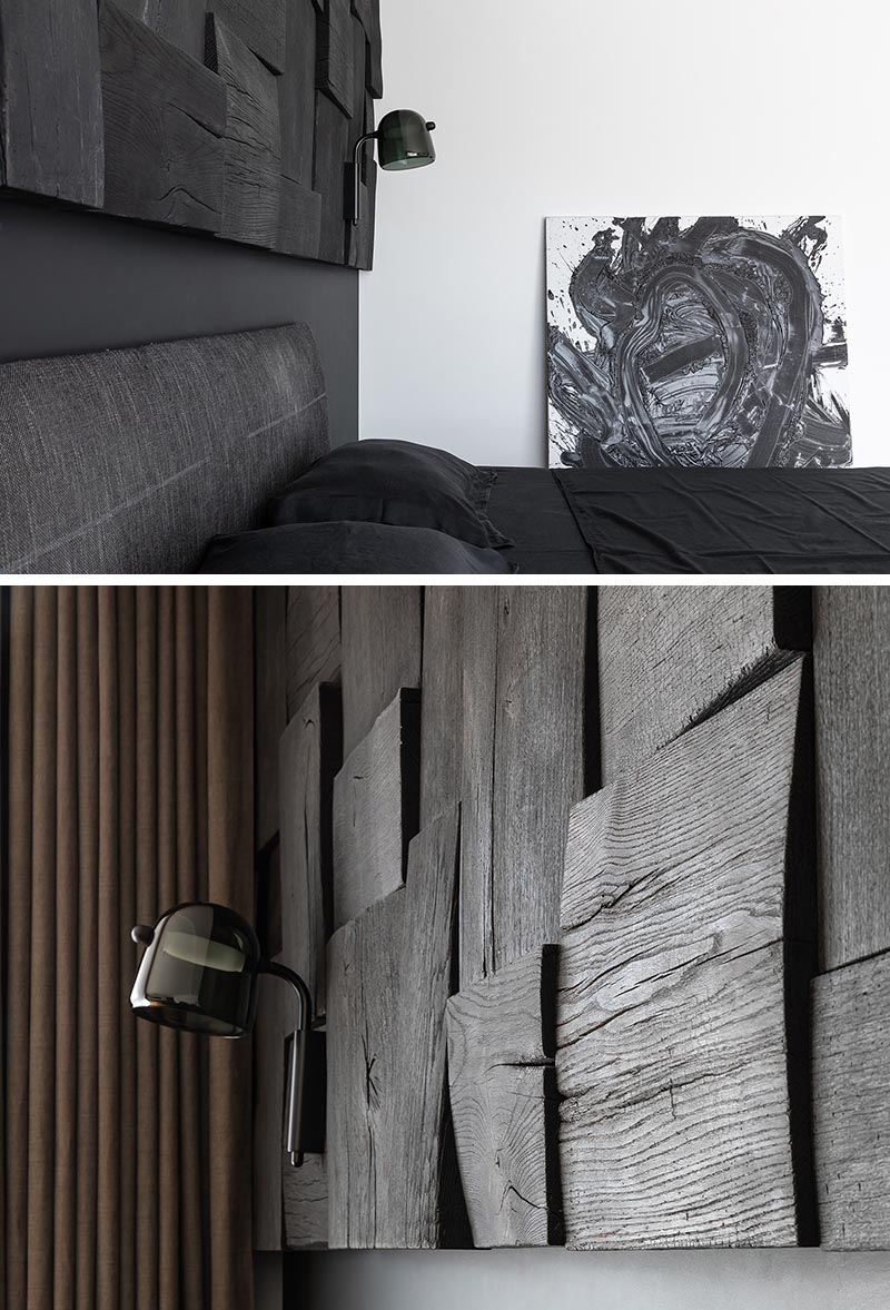 In this modern black bedroom, there's a black wall that provides a backdrop for the matching bed, while a blackened wood panel accent wall adds interest and texture to the room. #BlackBedroom #BlackAccentWall #BlackWoodAccentWall #WoodAccentWall #ModernBedroom