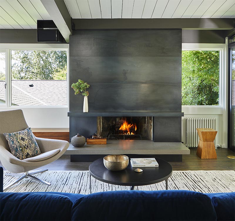 This modern blackened steel fireplace surround with a concrete hearth, creates an eye-catching detail in the living room.  #ModernFireplace #SteelFireplaceSurround #SteelFireplace #ConcreteHearth #ModernLivingRoom