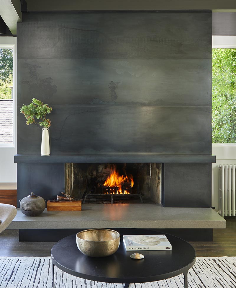 This modern blackened steel fireplace surround with a concrete hearth, creates an eye-catching detail in the living room.  #ModernFireplace #SteelFireplaceSurround #SteelFireplace #ConcreteHearth #ModernLivingRoom