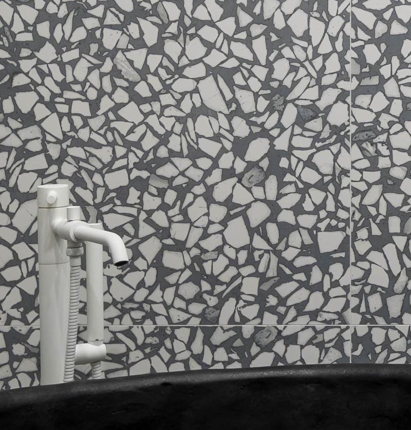 A grey and white aggregate large format tile has been installed in this modern bathroom, and covers the walls and floor, creating an almost art-like experience when using the bathroom. #GreyAndWhiteBathroom #GreyBathroom #BathroomIdeas #AggregateTiles