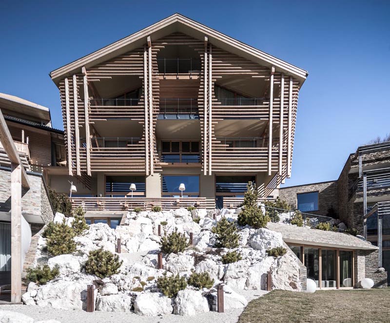 noa* network of architecture designed the renovation of Valentinerhof, a hotel in Italy, that showcases an exterior of smooth round logs. #ModernLogExterior #LogFacade #WoodFacade #HotelDesign