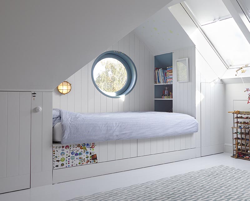 This modern kids bedroom has a built-it bed that's been tucked into one end of the room, creating an open play area that's softened by the use of a modern rug, and includes storage in the form of a closet and bookshelf. #KidsBedroom #ModernKidsBed #BuiltInBed #Interiors #BedroomDesign