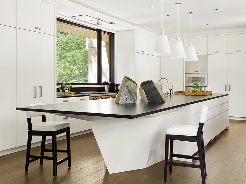 A modern geometric white kitchen island with a black countertop.