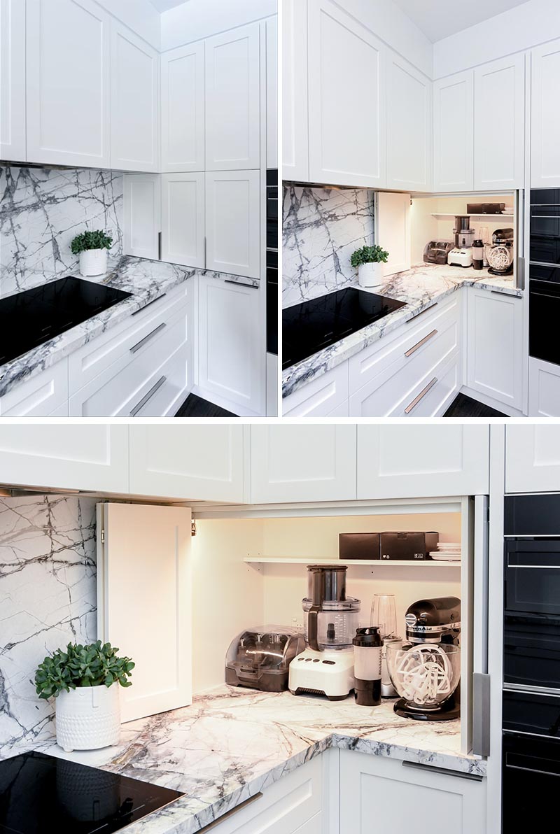 Tucked into the corner of this modern grey and white kitchen is an appliance garage that stores blenders and mixers. An interior light makes it easy to see the items within the cabinet. #KitchenDesign #KitchenIdeas #KitchenStorage #KitchenOrganization #ApplianceGarage