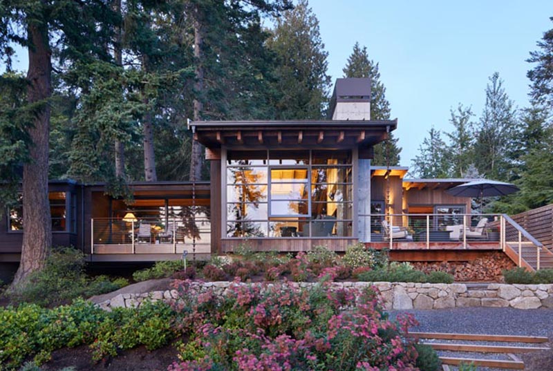 This modern house has deep overhanging eaves with exposed cedar rafters, offering protection from the weather and connecting to rain chains, aiding with the flow of rainwater into the garden. #OverhangingEaves #DeepEaves #ModernArchitecture #ExposedRafters#CedarRafters #HouseDesign #PacificNorthwest