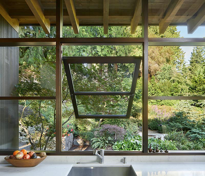 This modern house has deep overhanging eaves with exposed cedar rafters, offering protection from the weather and connecting to rain chains, aiding with the flow of rainwater into the garden. #OverhangingEaves #DeepEaves #ModernArchitecture #ExposedRafters#CedarRafters #HouseDesign #PacificNorthwest