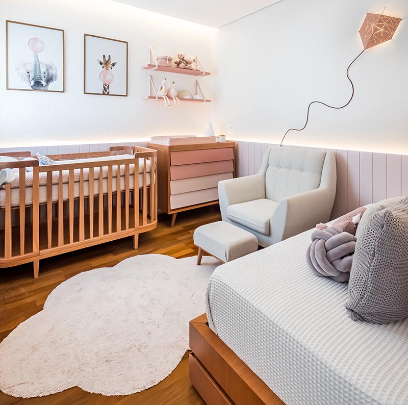 A palette of soft pinks and natural Jequitibá wood have been used throughout this modern nursery, while wood paneling with hidden indirect lighting helps to create a sense of warmth. #ModernNursery #PinkNursery #GirlsBedroom #InteriorDesign #Interiors #NurseryRoom #BabyRoom