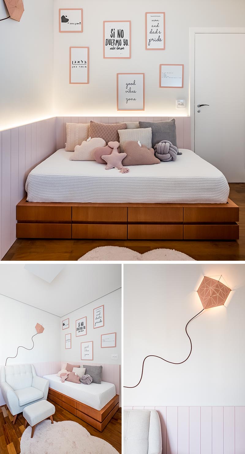 A palette of soft pinks and natural Jequitibá wood have been used throughout this modern nursery, while wood paneling with hidden indirect lighting helps to create a sense of warmth. Upon entering the nursery, there's a custom-designed day bed with storage drawers below it, and a kite lamp on the wall adds a creative and playful touch. #ModernNursery #PinkNursery #GirlsBedroom #InteriorDesign #Interiors #NurseryRoom #BabyRoom