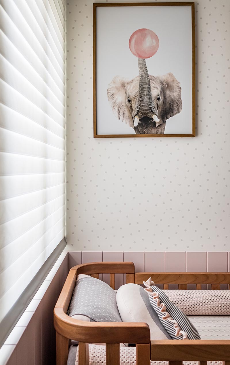In this modern nursery with a pink palette, a neutral wallpaper with a spotted pattern covers the walls, while fun nursery art in the form of animal prints liven up the space. #ModernNursery #PinkNursery #GirlsBedroom #InteriorDesign #Interiors #NurseryRoom #BabyRoom