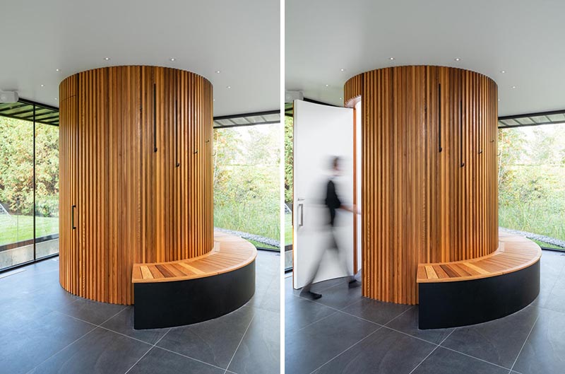Tucked into one corner of this modern pool house, is a cylindrical bathroom with a wood bench wrapped around it on one side. Designed as a sculptural element within the pool house, the bathroom is clad in red cedar cleats, adding a sense of warmth to the open space that surrounds it. #Bathroom #RedCedar #RoundBathroom #CircularBathroom #PoolHouse