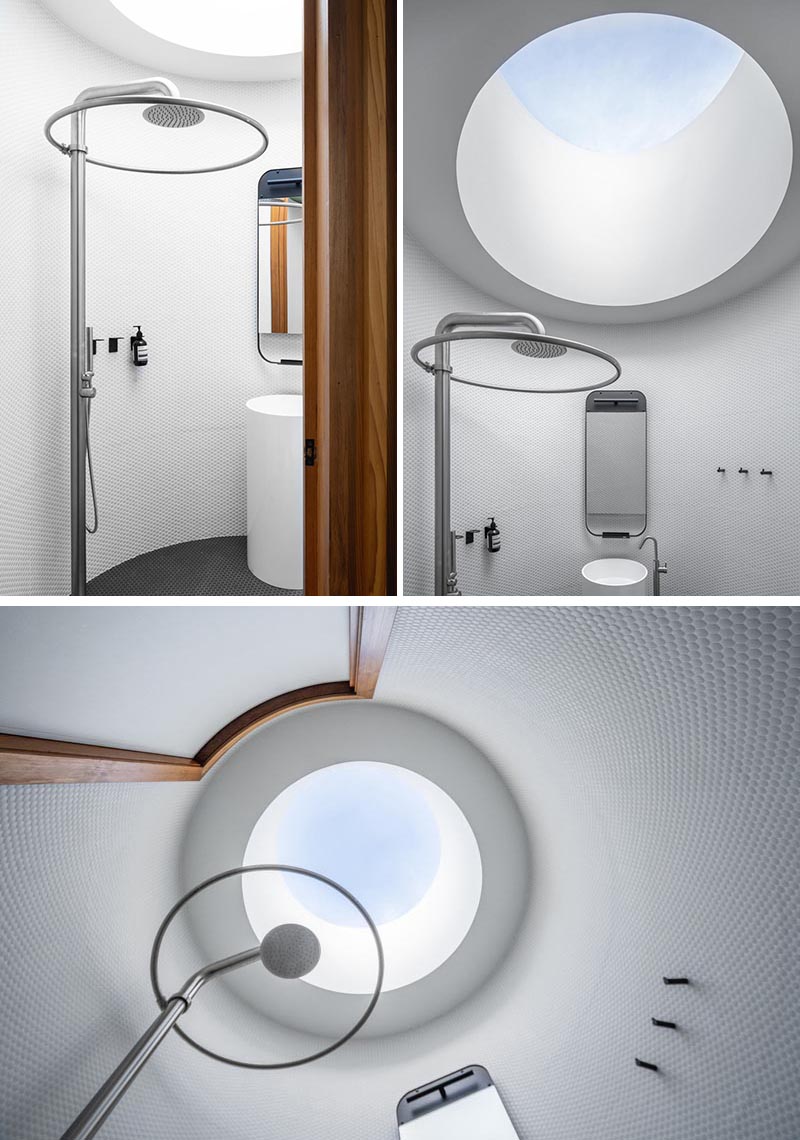 This modern circular bathroom has walls of white penny tiles, and a round skylight above the shower that reflects the overall shape of the bathroom. #RoundSkylight #CircularSkylight #Bathroom #RoundBathroom #PennyTiles