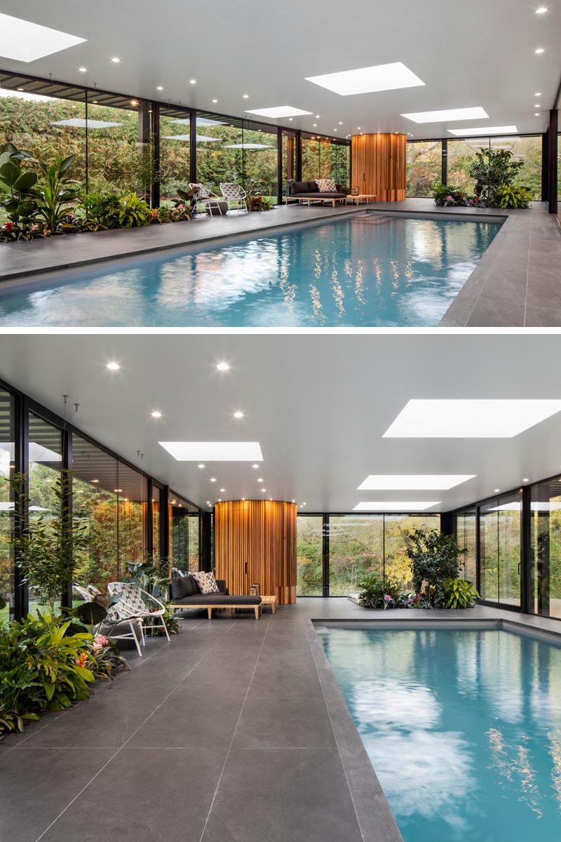 Inside this modern pool house, there's skylights that scatter the ceiling, a deck with designated places for lounging, and planters filled with lush tropical plants of varying heights. #PoolHouse #Planters #BuiltInPlanters #SwimmingPool