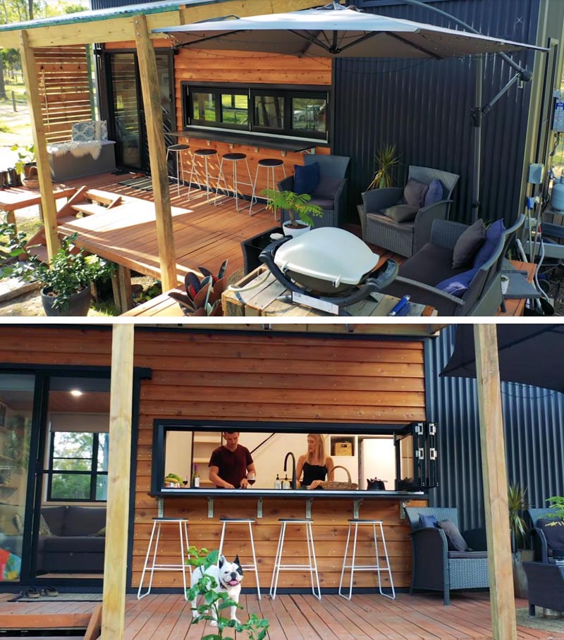 Designed for relaxing, the front porch of this tiny house is home to a casual lounge area with a bbq and a bar area. #TinyHouse #TinyHousePorch #TinyHouseDeck