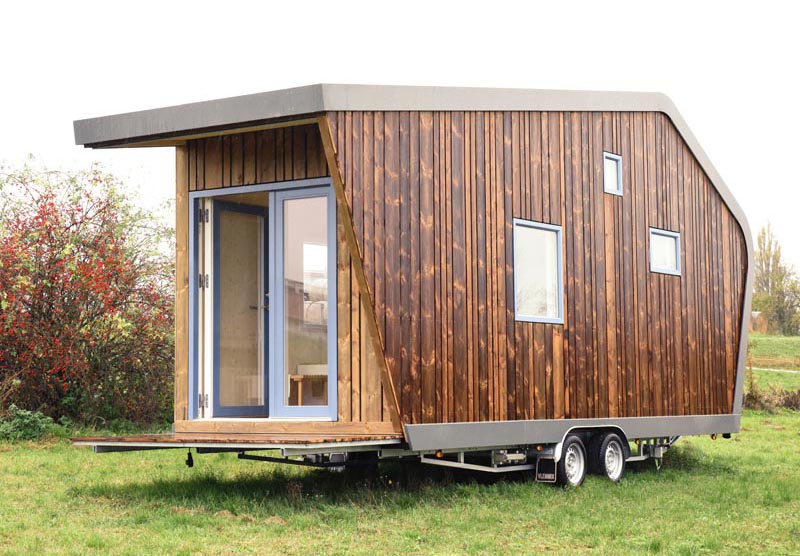 This modern tiny house is clad in wood and inside there's a dining area, kitchen, bathroom, desk, living area, and a lofted bedroom. #TinyHouse #ModernTinyHouse #TinyHome #SmallLiving #WoodSiding