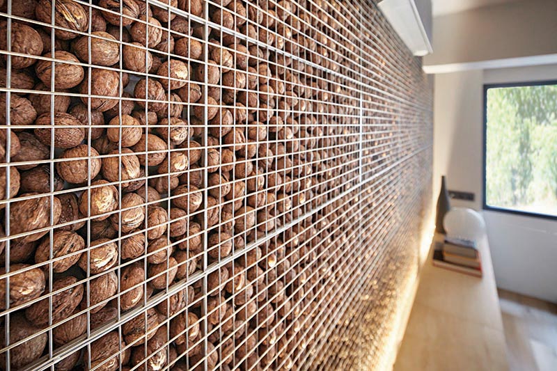 This modern home office features an eye-catching and unique accent wall that's created by filling a metal cage with walnuts, also known as a gabion. #AccentWall #UniqueAccentWall #FeatureWall #Walnuts #Gabion #HomeOffice