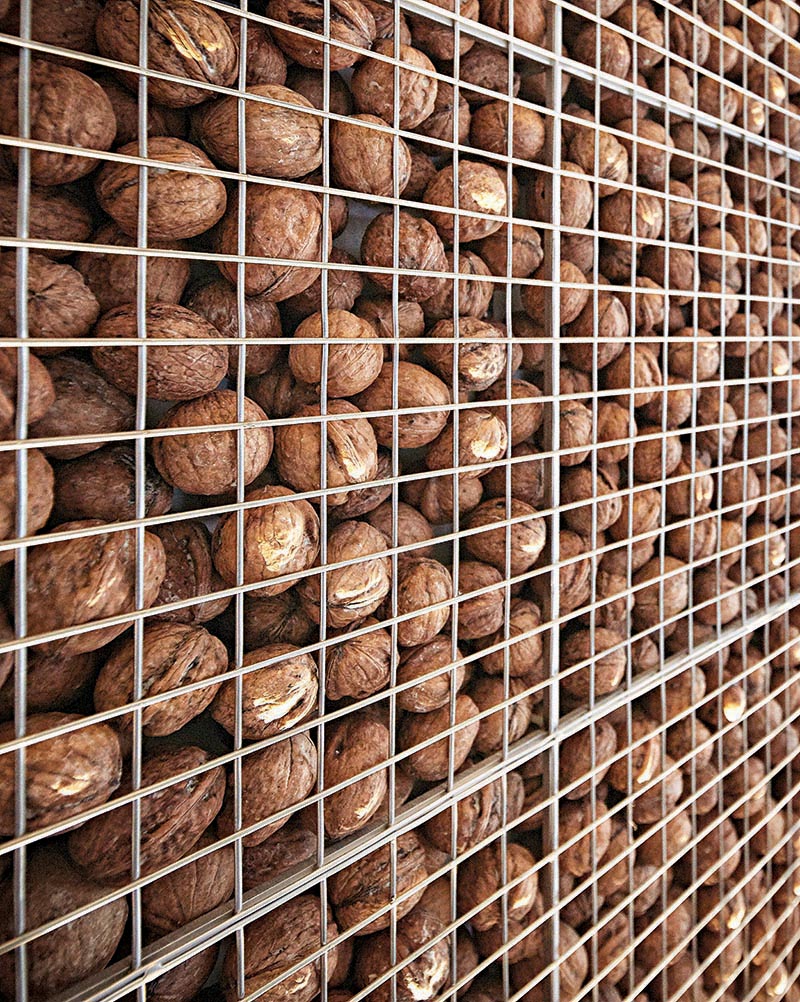 This modern home office features an eye-catching and unique accent wall that's created by filling a metal cage with walnuts, also known as a gabion. #AccentWall #UniqueAccentWall #FeatureWall #Walnuts #Gabion #HomeOffice