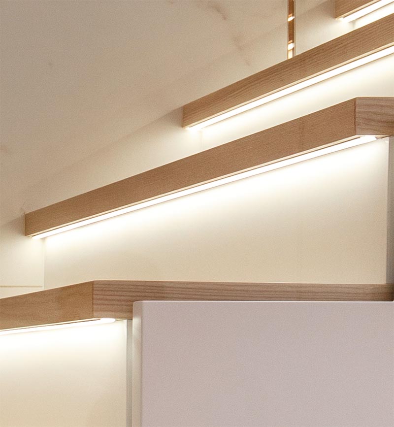 These modern wood stairs have a tread with an overhang (or nosing) that extends past the riser, allowing room for a thin strip of lighting to be attached to the underneath surface. #Stairs #StairsWithLighting #StairDesign #HiddenLighting