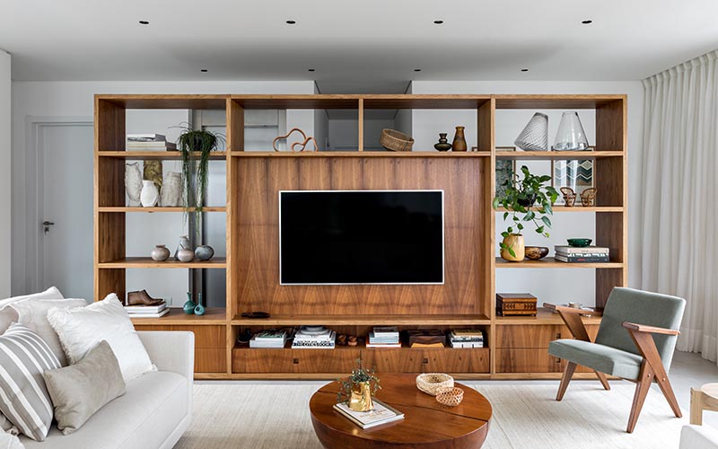 This modern room divider, made from Freijó wood, creates a space to welcome residents and visitors before reaching the open floor plan of the living room, kitchen, and dining area. From the living room side, the shelving unit provides a designated area for the TV in the living room, as well as storage in the form of bookshelves and drawers. #RoomDivider #WoodRoomDivider #WoodPartition #WoodShelving #LivingRoom #InteriorDesign #Interiors