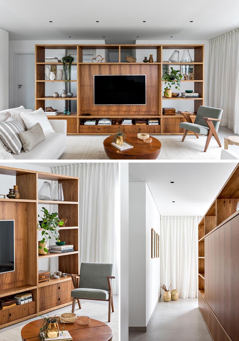 This modern room divider, made from Freijó wood, creates a space to welcome residents and visitors before reaching the open floor plan of the living room, kitchen, and dining area. From the living room side, the shelving unit provides a designated area for the TV in the living room, as well as storage in the form of bookshelves and drawers. #RoomDivider #WoodRoomDivider #WoodPartition #WoodShelving #LivingRoom #InteriorDesign #Interiors