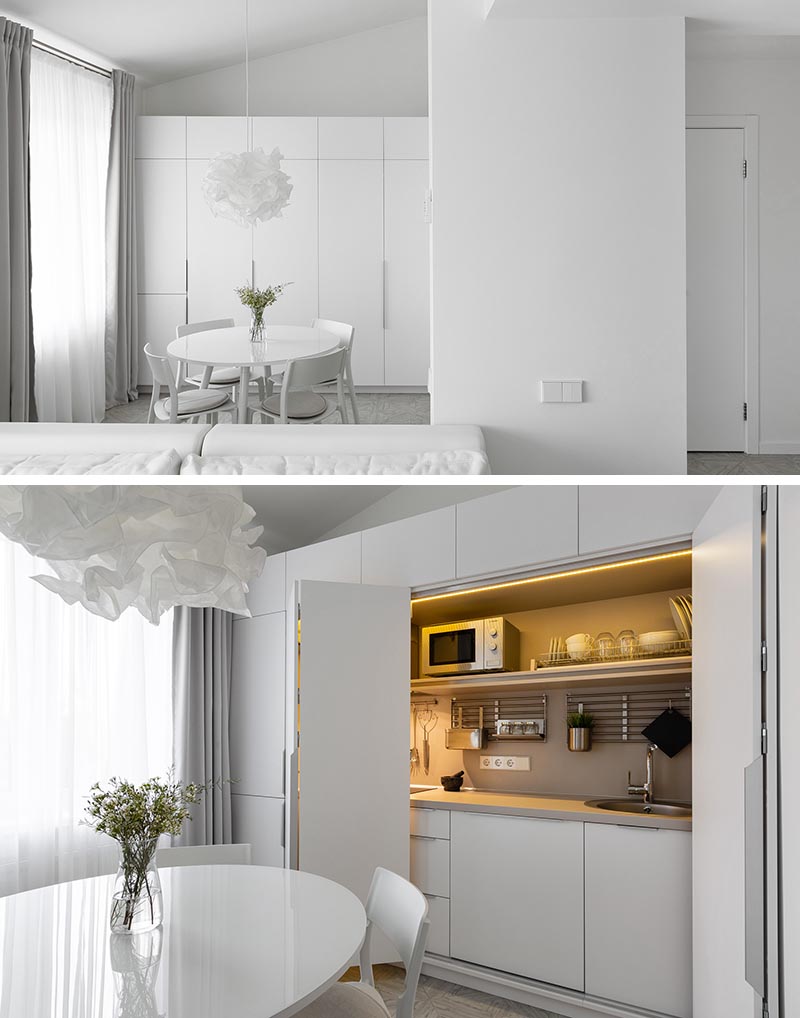 This modern and minimalist white apartment has the kitchen hidden within a closet in the dining area. #MinimalistKitchen #HiddenKitchen #KitchenDesign