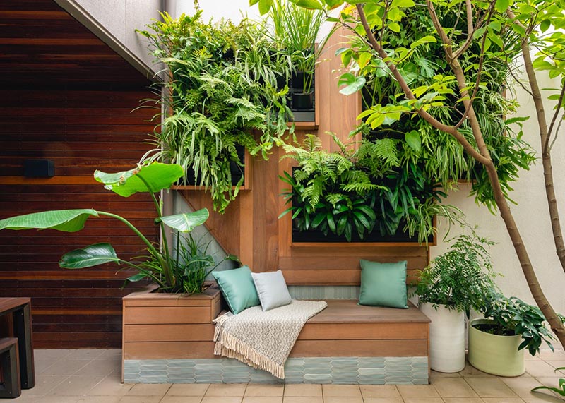 The main feature of the small courtyard is a custom-designed plant wall with a built-in bench. The vertical plant wall has framed greenery, while beside the bench is a planter that also acts as a small backrest when paired with cushions. #SmallCourtyard #SmallOutdoorSpace #PlantWall #VerticaPlantWall #GreenWall #BuiltInBench #Landscaping #LandscapeDesign