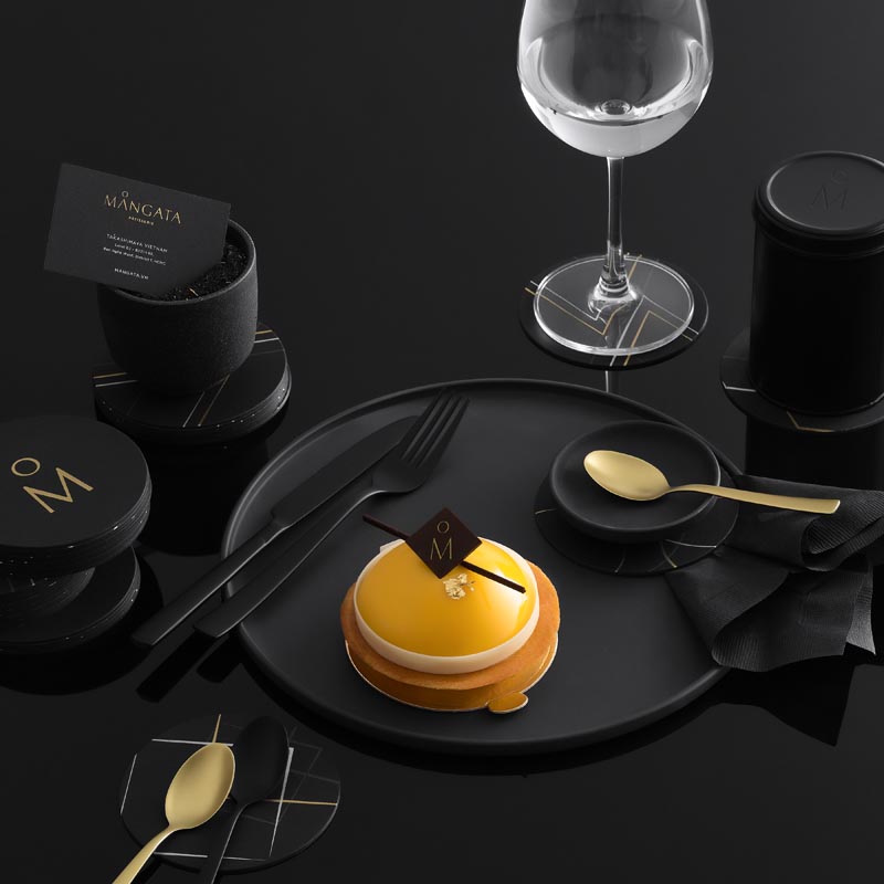 Matte black and gold plates and cutlery for a patisserie.