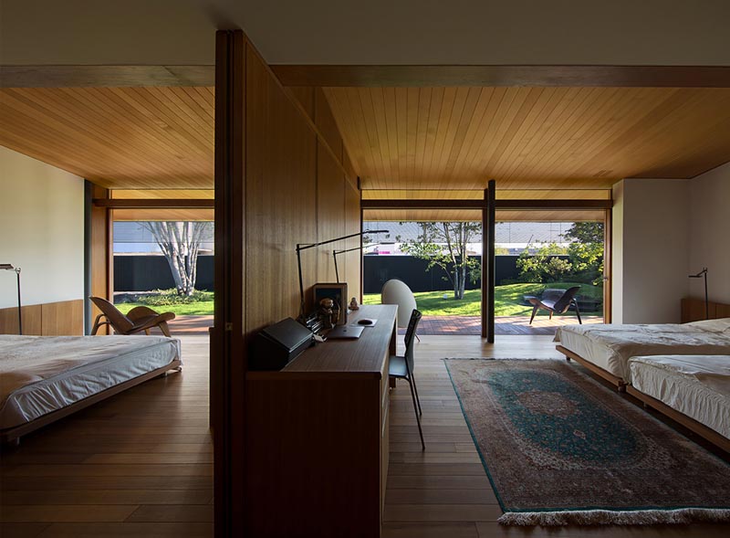 A wood wall separates two bedrooms and includes a desk.