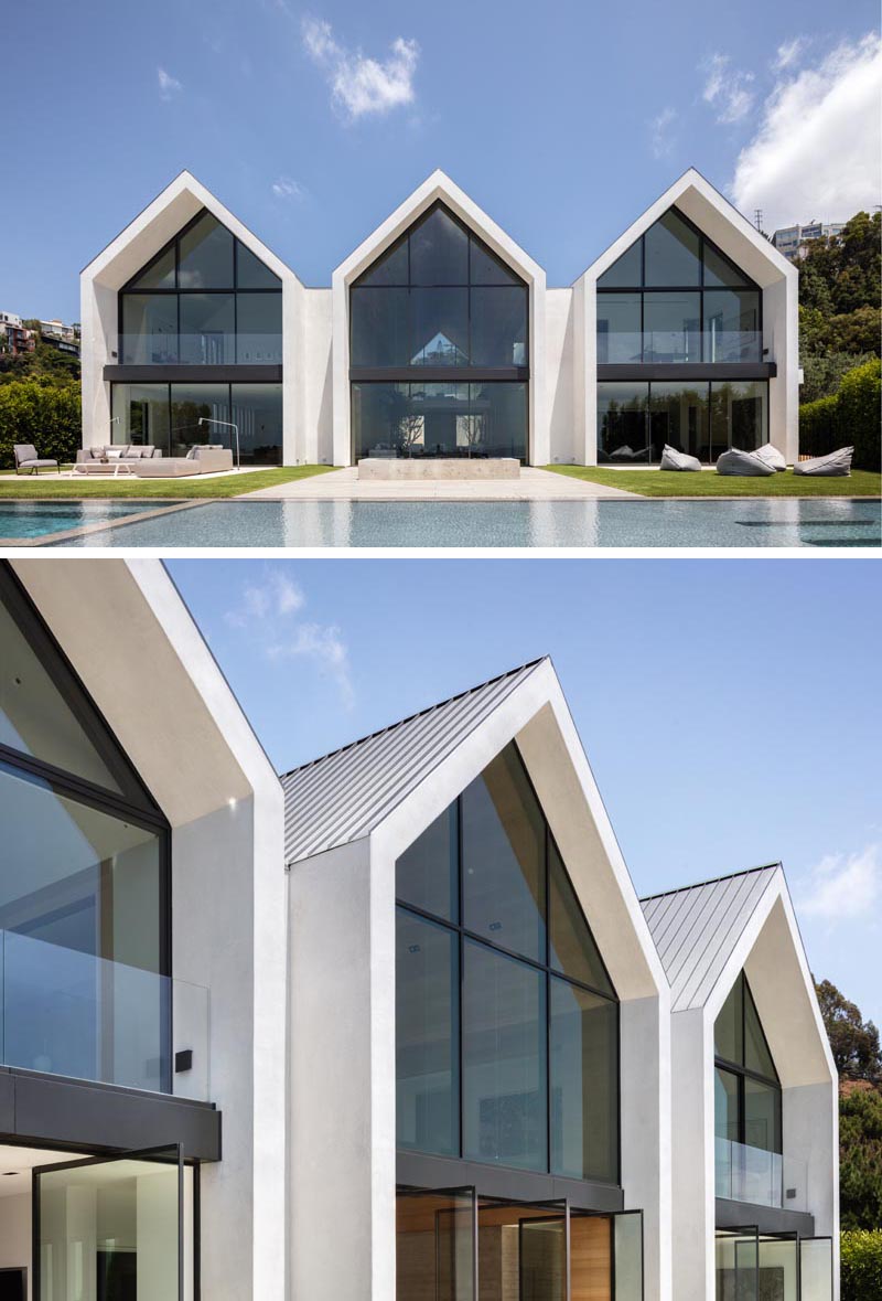 The eye-catching gabled design of this modern barn-inspired house, is easily seen upon approach to the house, and once inside, the wall of windows and doors at the other end of the wood-lined great room showcase the swimming pool and view. #ModernHouse #ModernArchitecture #HouseDesign #GabledRoof #GreatRoom