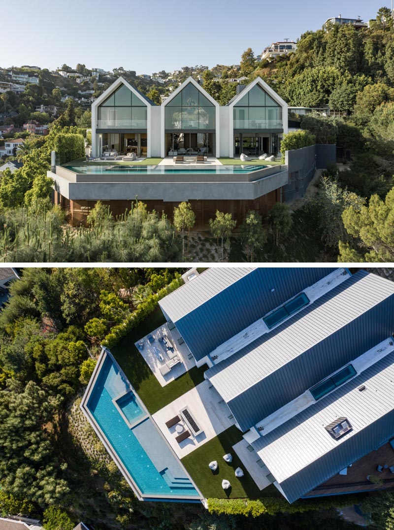 The eye-catching gabled design of this modern barn-inspired house, is easily seen upon approach to the house, and once inside, the wall of windows and doors at the other end of the wood-lined great room showcase the swimming pool and view. #ModernHouse #ModernArchitecture #HouseDesign #GabledRoof #GreatRoom