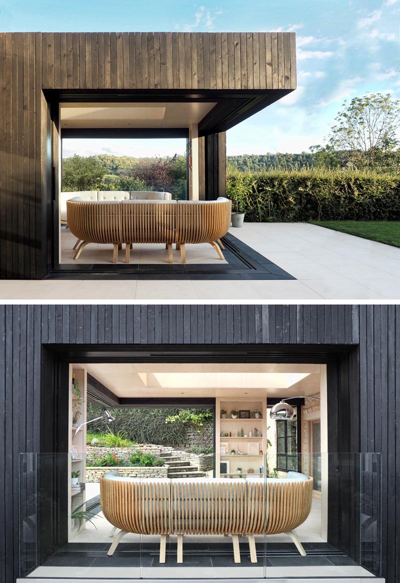 The sliding glass doors of thi modern extension disappear entirely behind three timber bookcases, that also provide vertical support to the structure. When open, these sliding doors create an outdoor living room that opens up to the garden. #OutdoorLivingRoom #ModernExtension #HomeOffice #ReadingRoom