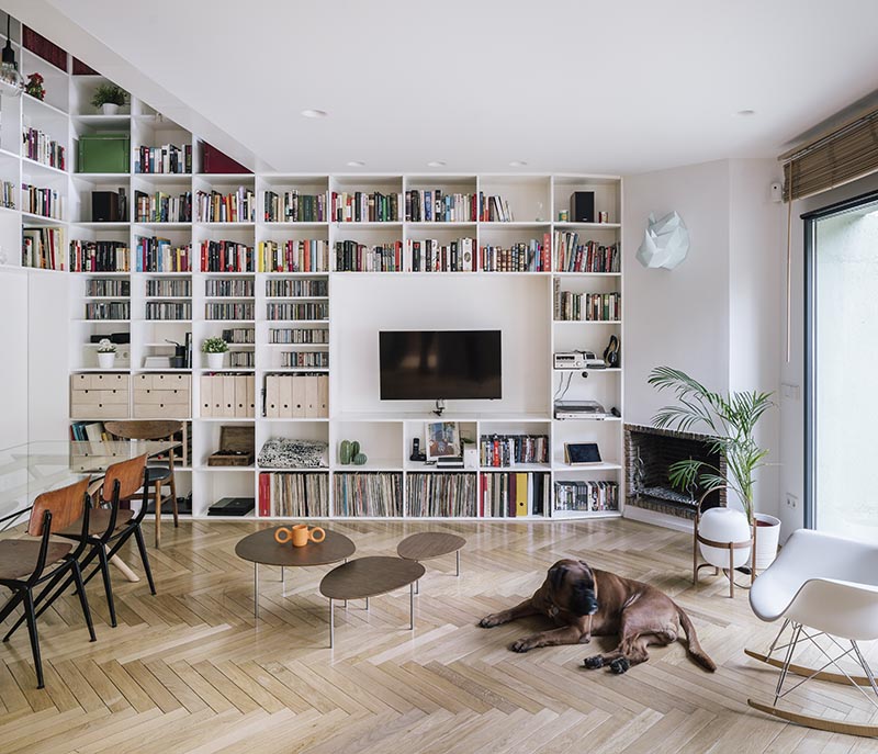 This modern white double-height bookshelf covers both the ground and first floor of this house. Starting in the open plan living room and dining room, the bookshelf wraps around the walls before traveling vertically towards the first floor of the house. #Bookshelf #DoubleHeightBookshelf #ShelvingIdeas #BuiltInBookshelf