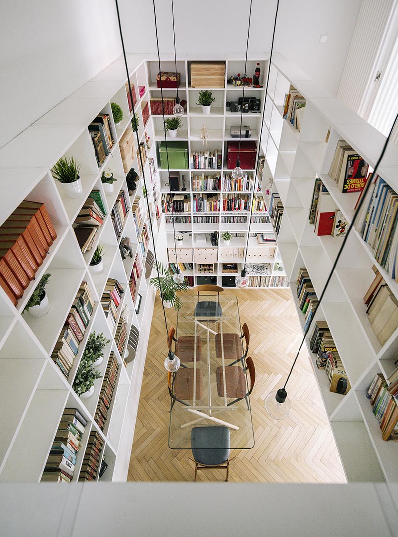 This modern white double-height bookshelf covers both the ground and first floor of this house. Starting in the open plan living room and dining room, the bookshelf wraps around the walls before traveling vertically towards the first floor of the house. #Bookshelf #DoubleHeightBookshelf #ShelvingIdeas #BuiltInBookshelf