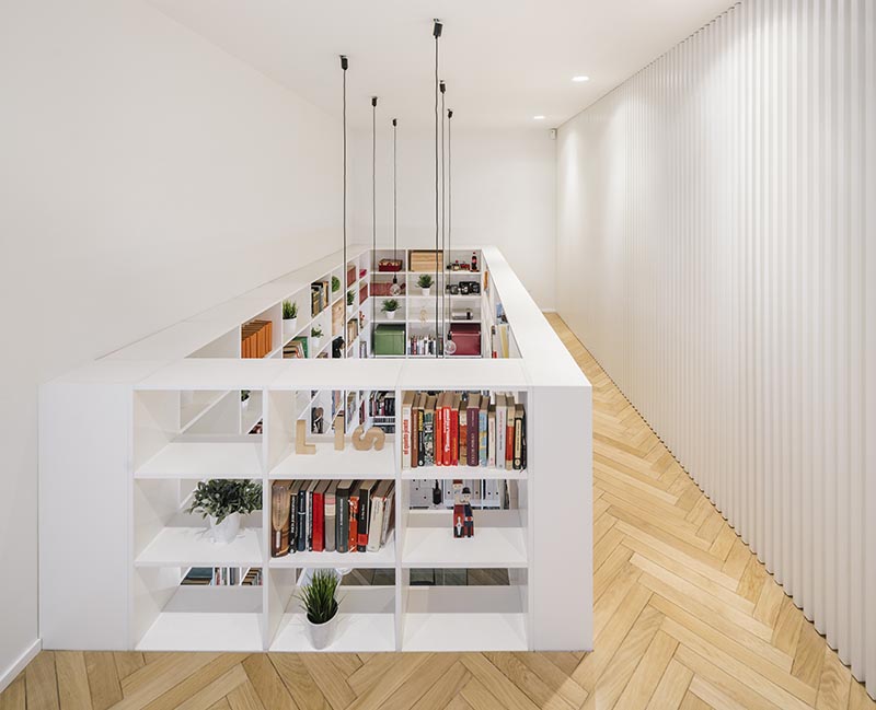 The top of this double-height bookshelf transforms into a safety railing for the walkway that leads to the bedrooms and bathrooms on the first floor. #Bookshelf #Railing #SafetyRailing