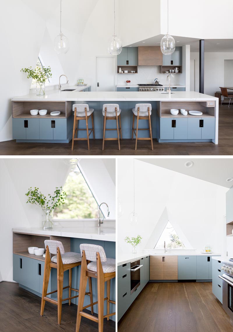 The open kitchen in this renovated geodesic dome house showcases custom cabinetry that consists of a mix of blue and bamboo slab fronts, with cutouts for handles. A quartz countertop and backsplash finish out the space and keep it bright. #ModernKitchen #BlueKitchenCabinets #QuartzCountertop #GeodesicDomeInterior