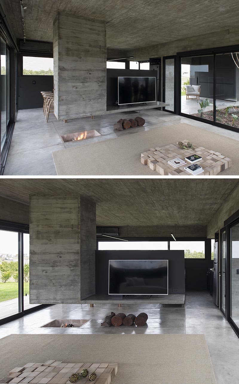 Designed as a sculptural element that separates the dining room and the living room, this modern hanging concrete divider has a chimney built into it on one end, and the other is a platform for holding the television. Underneath, the fireplace has been built into the ground. #Fireplace #RoomDivider #ConcreteDivider #HangingConcreteChimney #TVStand #Concrete