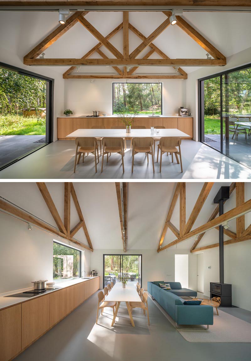 Inside this modern house, the minimalist kitchen, dining area, and living room all share the same space, while the roof structure has been left exposed. #OpenPlanInterior #MinimalistKitchen #DiningRoom #ExposedCeiling #LivingRoom #Fireplace