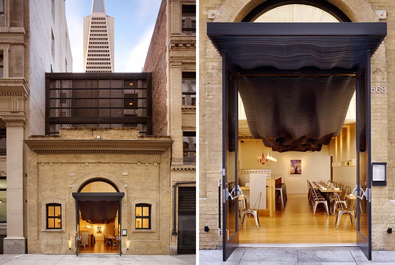 The striking black undulating sculptural detail travels from the interior of the restaurant out to the facade, where it covers the entryway and adds a modern element to the historic building. #BuildingFacade #SculpturalFacade #RestaurantDesign