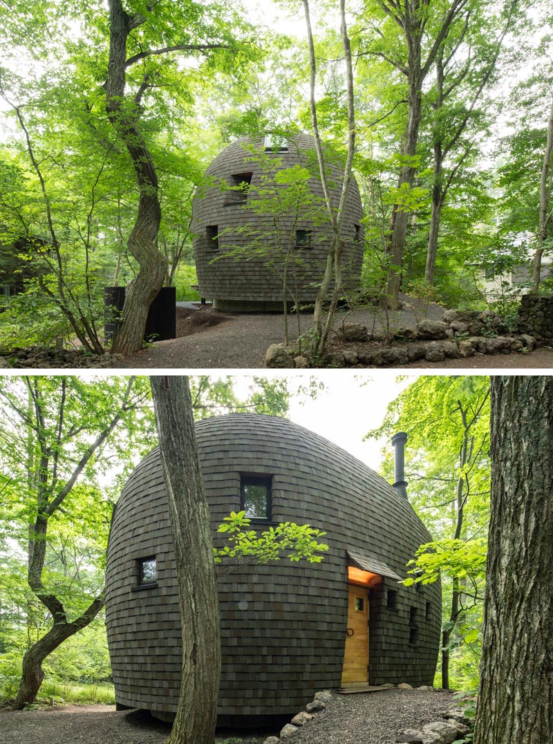 This small curved house was built using materials like local wood and clay, and crafted using traditional building techniques. Dark wood shingles cover the curved exterior, while recessed windows and skylights capture small amounts of natural light, and a light wood door welcomes guests. #CurvedHouse #SmallHouse #Shingles #Windows #Architecture