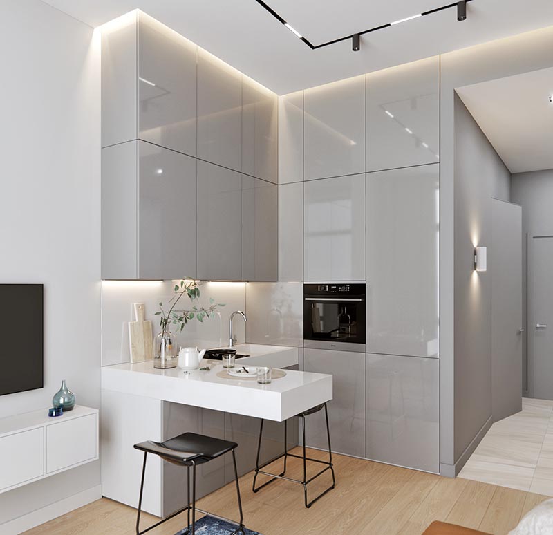 A small kitchen with an L-shaped countertop, integrated fridge, minimalist grey cabinets, hidden lighting, and a cantilevered peninsula for dining. #SmallKitchen #TinyKitchen #KitchenDesign #KitchenLayout